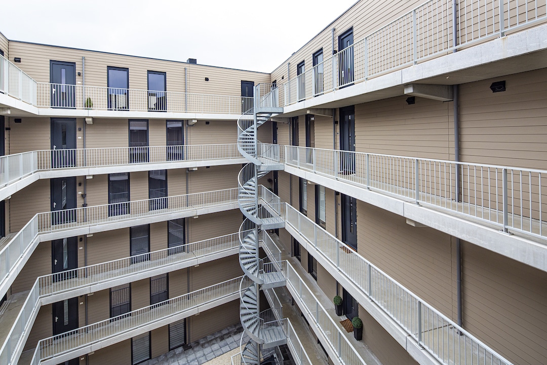 Hardie Plank szálcement homlokzatburkolat modern társasház belső udvarában, fa hatású vízszintes burkolatkiosztással