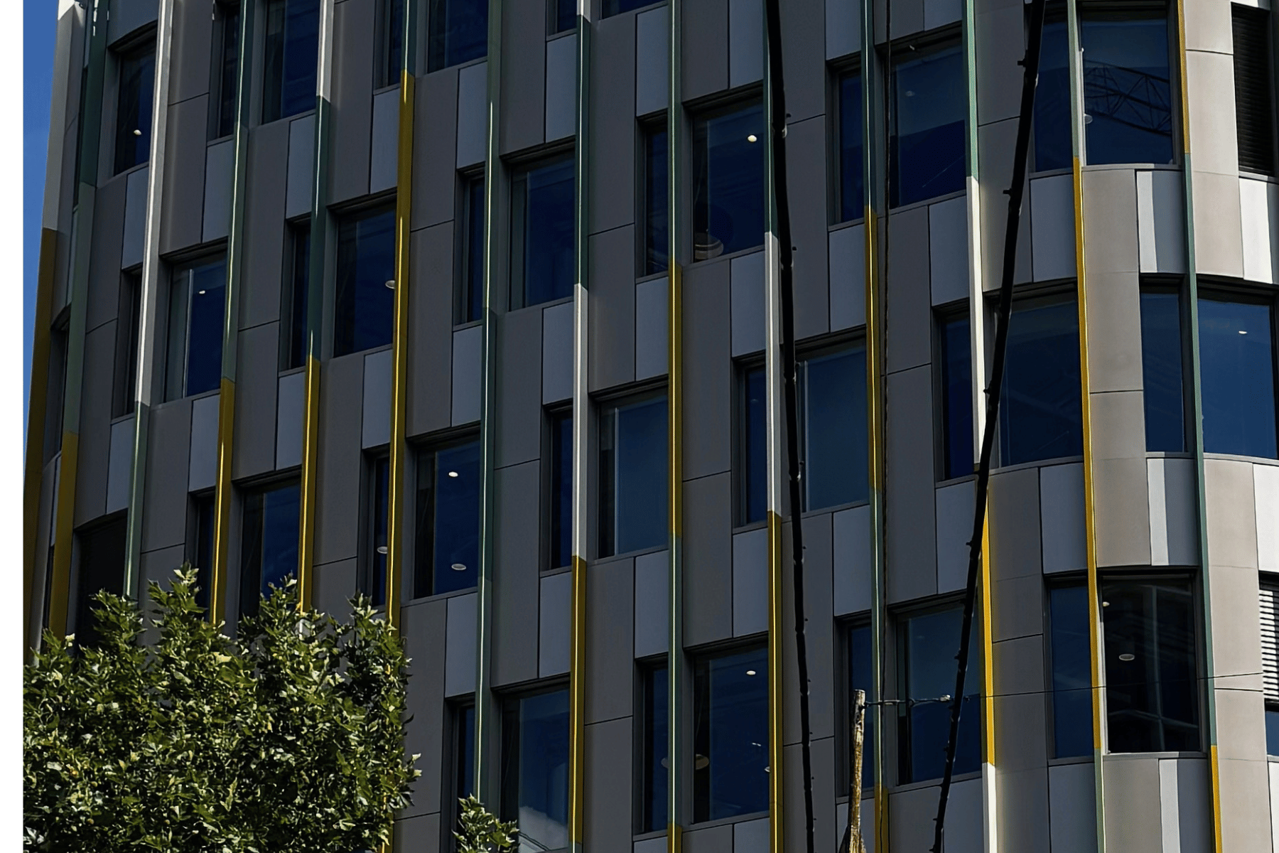 A Pillar irodaház homlokzati részlete ezüstszínű panelekkel, sárga és halványzöld függőleges lamellákkal